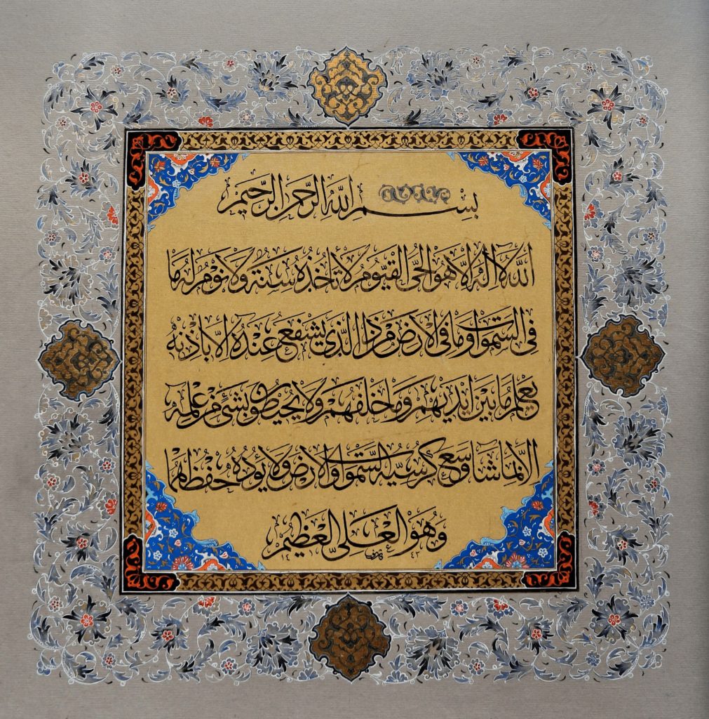 Verse 255 of Surah Al-Baqarah is depicted in black ink in Thuluth Jeli on ahar/muqahar paper. The calligraphy is on a beige-colored background. The Turkish style tezhib/illumination in blue, brown and orange ornaments the calligraphy.
