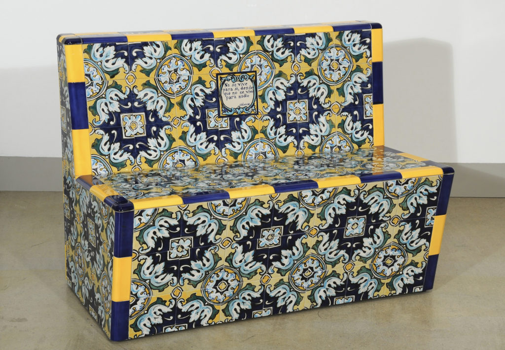 Bench with no arms made of ceramics. Principal colors are blue and yellow, with arabesque shapes in light blue, green, and light yellow with central florets. 