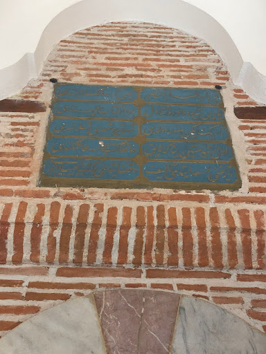 Gold colored Ottoman inscriptions are painted on a blue background embedded into a brick wall.