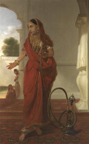  A colour painting of a dancing girl holding a hookah while standing next to it. Two women in the corner of the background are talking to each other but have their faces towards the dancing girl suggesting that they are peering in. White marble columns outline the right side of the painting. The hookah’s design is also luxurious, depicting wealth in the place she is standing. She is wearing a deep red sari. Unlike the photographs above, her midriff is showing which signals the position of the painter as desiring the woman. Her sari covers her head and on top of it rests a headpiece that goes all over her hair and ends up outlining her hairline on her forehead. She is wearing several necklaces, each different length but similar texture. Her nose ring has white pearlish adornments. Her earrings are dangling and gold. Where her blouse sleeves end, she is wearing multiple armlets. Her gold bangles tell us of her financial might. She is wearing pointed anklets and beaded anklets. Her blouse is golden with lines of orange across it.

