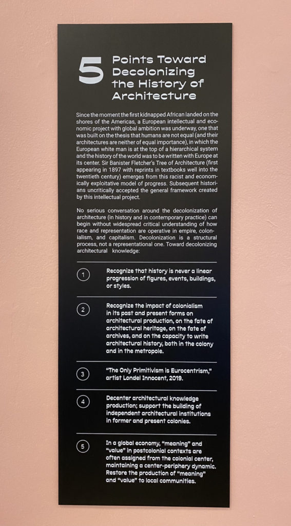 A black rectangular panel with white text lays out Elshahed’s 5 points toward decolonizing the history of architecture: 
Since the moment the first kidnapped African landed on the shores of the Americas, a European intellectual and economic project with global ambition was underway, one that was built on the thesis that humans are not equal (and their architectures are neither of equal importance), in which the European white man is at the top of a hierarchical system and the history of the world was to be written with Europe at its center. Sir Banister Fletcher's Tree of Architecture (first appearing in 1897 with reprints in textbooks well into the twentieth century) emerges from this racist and economically exploitative model of progress. Subsequent historians uncritically accepted the general framework created by this intellectual project.
No serious conversation around the decolonization of architecture (in history and in contemporary practice) can begin without widespread critical understanding of how race and representation are operative in empire, colonialism, and capitalism. Decolonization is a structural process, not a representational one. Toward decolonizing architectural knowledge:
(1) Recognize that history is never a linear progression of figures, events, buildings, or styles.
(2) Recognize the impact of colonialism in its past and present forms on architectural production, on the fate of architectural heritage, on the fate of archives, and on the capacity to write architectural history, both in the colony and in the metropole.
(3) "The Only Primitivism is Eurocentrism," artist Londel Innocent, 2019.
(4) Decenter architectural knowledge production; support the building of independent architectural Institutions in former and present colonies.
(5) In a global economy, "meaning" and "value" in postcolonial contexts are often assigned from the colonial center, maintaining a center-periphery dynamic. Restore the production of "meaning" and "value" to local communities.
