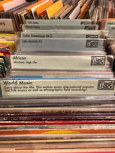 An image of records with divider labels. The first label reads, "World Music: Sorry about the title. This section spans international popular and folks musics as well as ethnographic field recordings. 